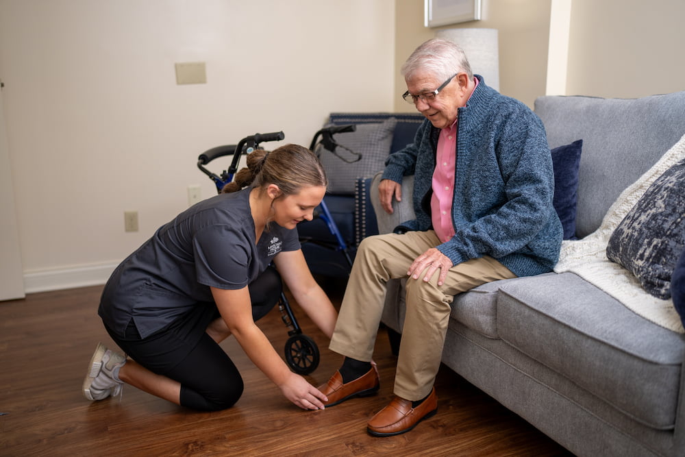 Team member putting a shoe on a senior male resident