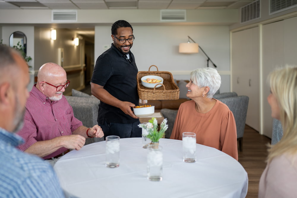 Team member using his job skills to serve residents a meal at table