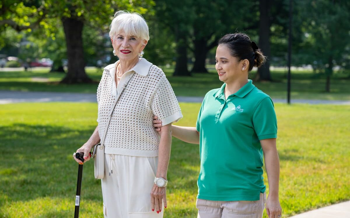 CNA enjoys a walk outside with an elderly woman
