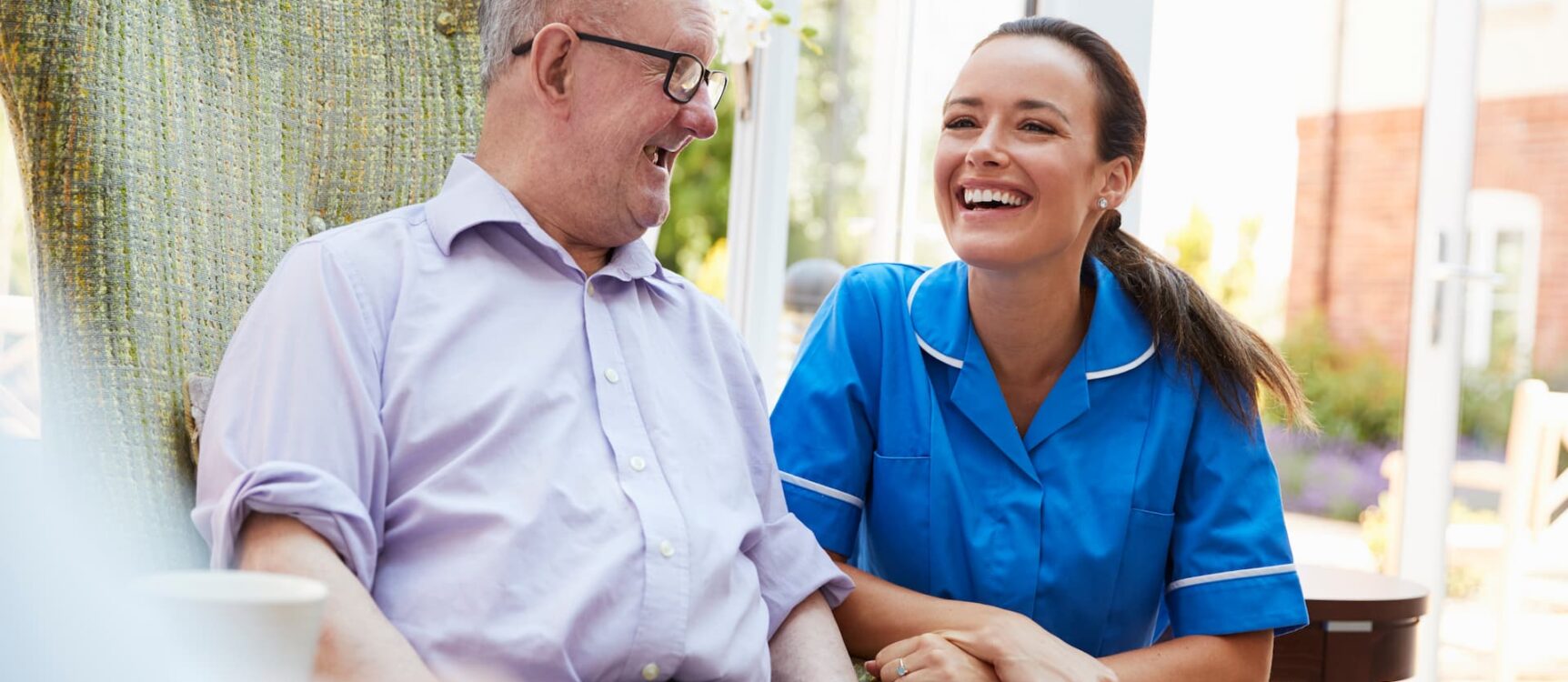 Caregiver smiling with an aging adult in a senior living community.